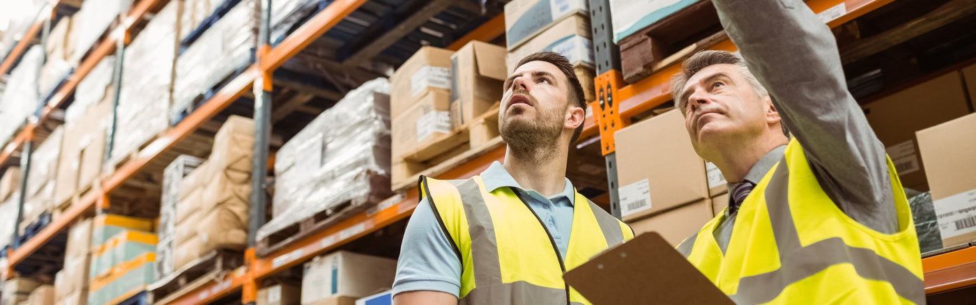 two people wearing high visibility vests in warehouse