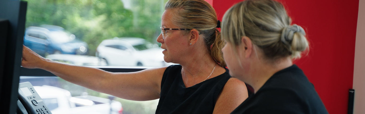 Two people in an office environment looking at a computer screen