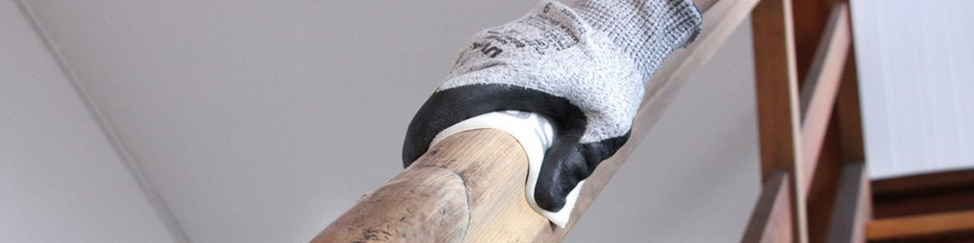 Gloved hand using soft sanding roll on wooden banister